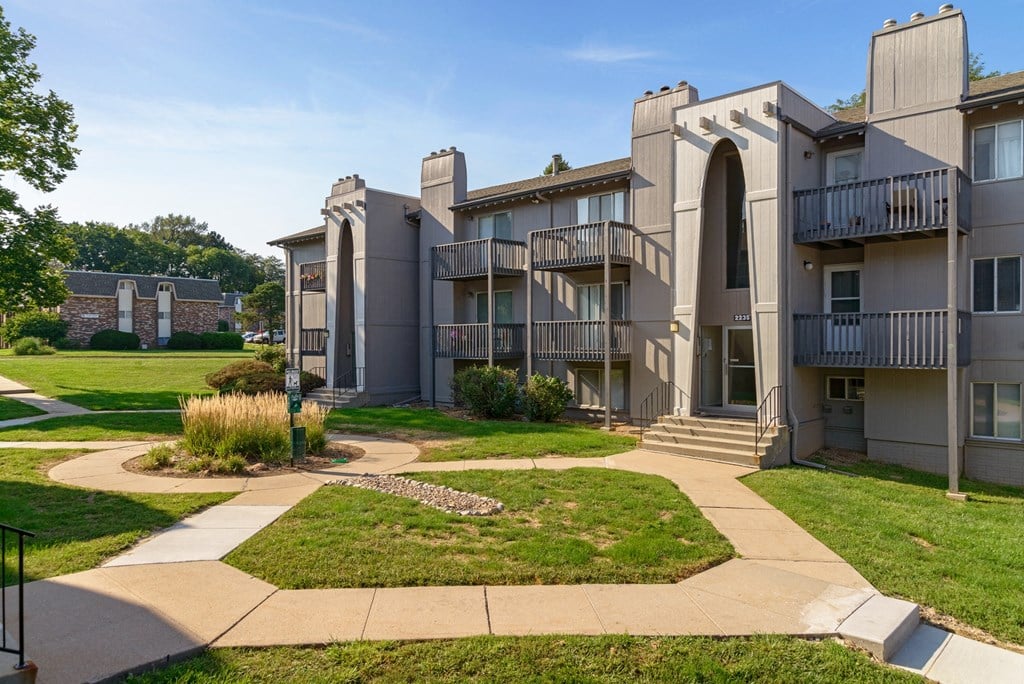 an exterior view of an apartment building with green grass and sidewalks