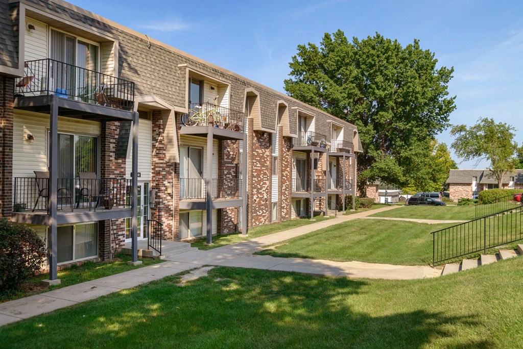 a row of brick apartment buildings with balconies and grass and trees