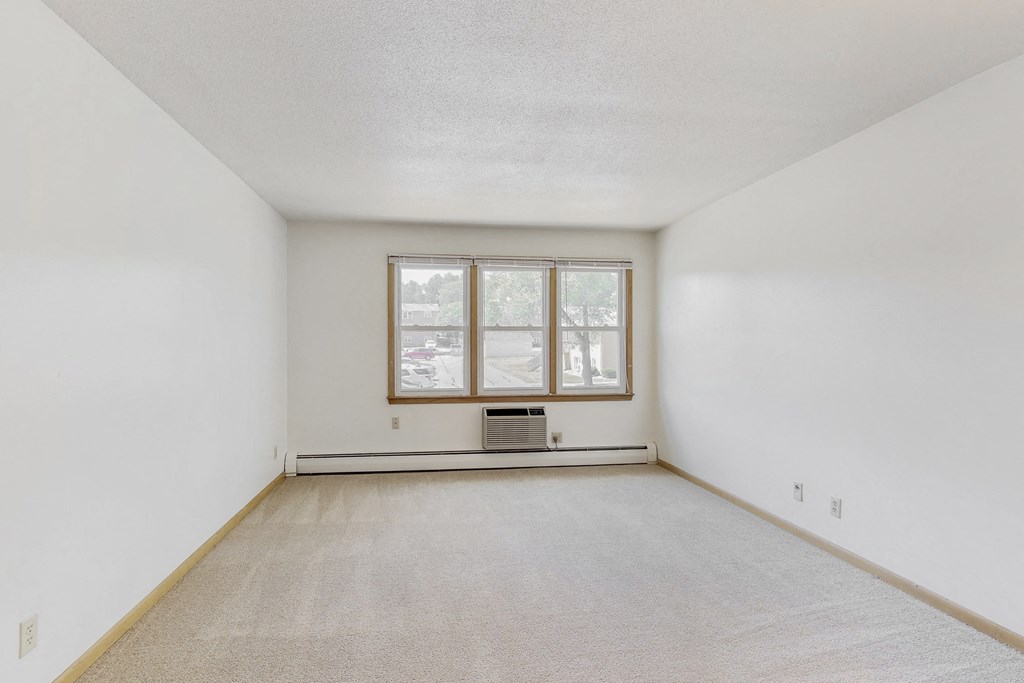 a spacious living room with white walls and a window