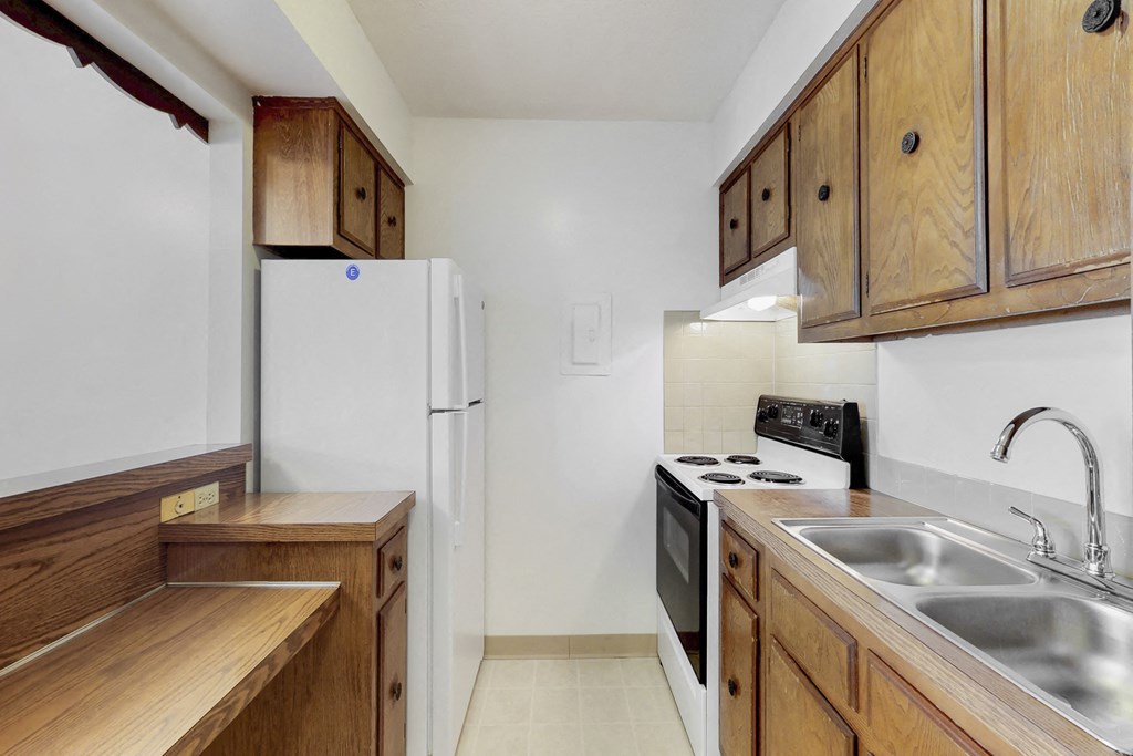 a kitchen with wooden cabinets and a sink and a refrigerator
