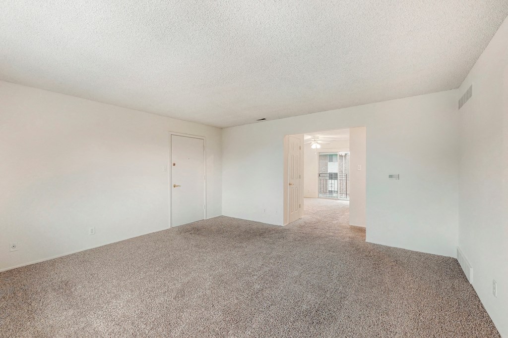 an empty living room with carpet and white walls
