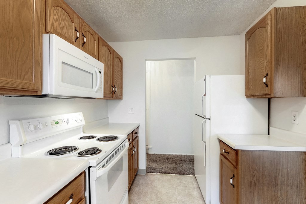 an empty kitchen with white appliances and wooden cabinets