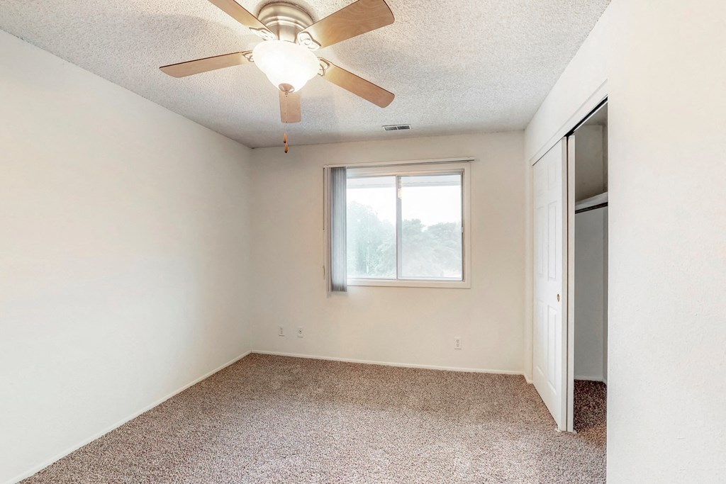 an empty room with a ceiling fan and a window
