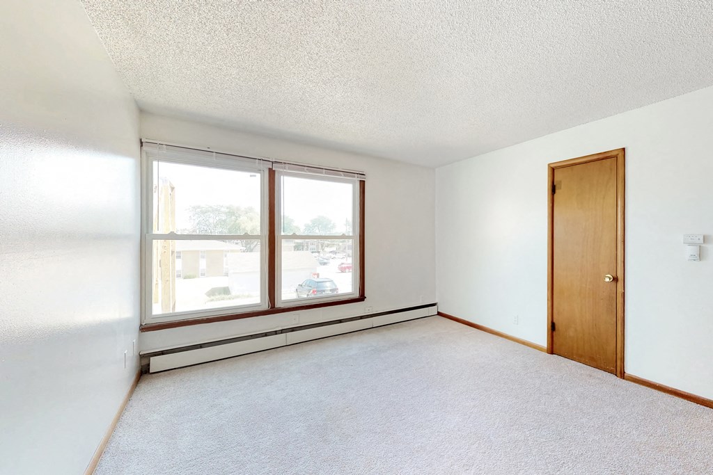 an empty living room with two windows and a door