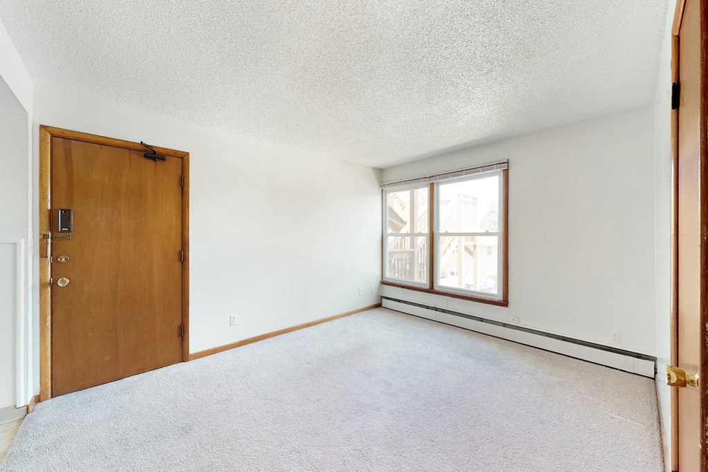 an empty living room with a wooden door and a window