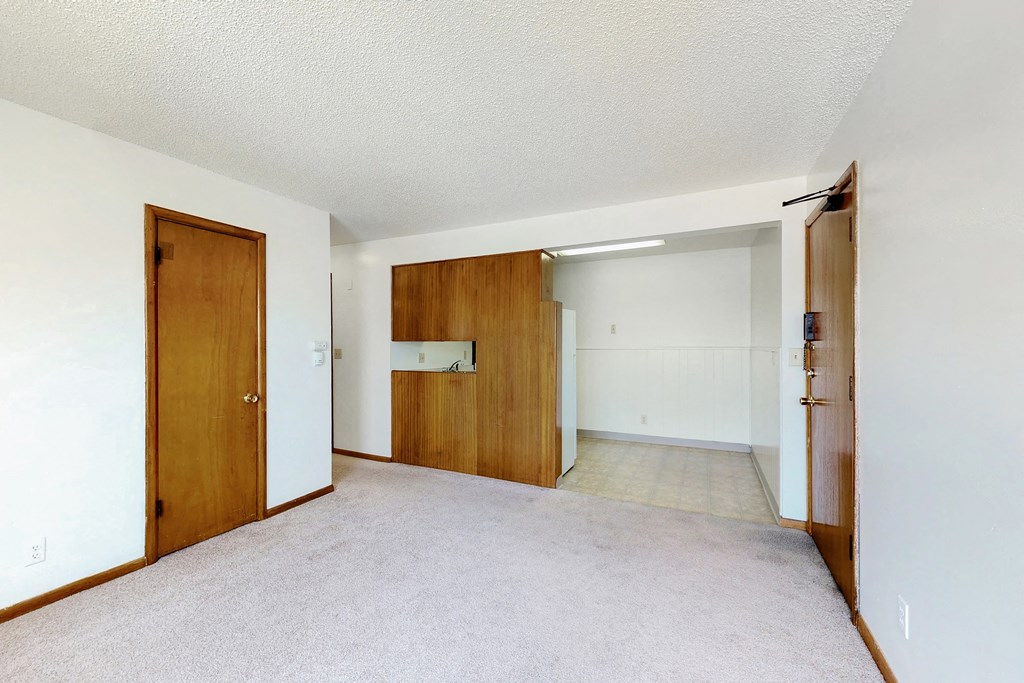 an empty living room and hallway with a door to a bedroom