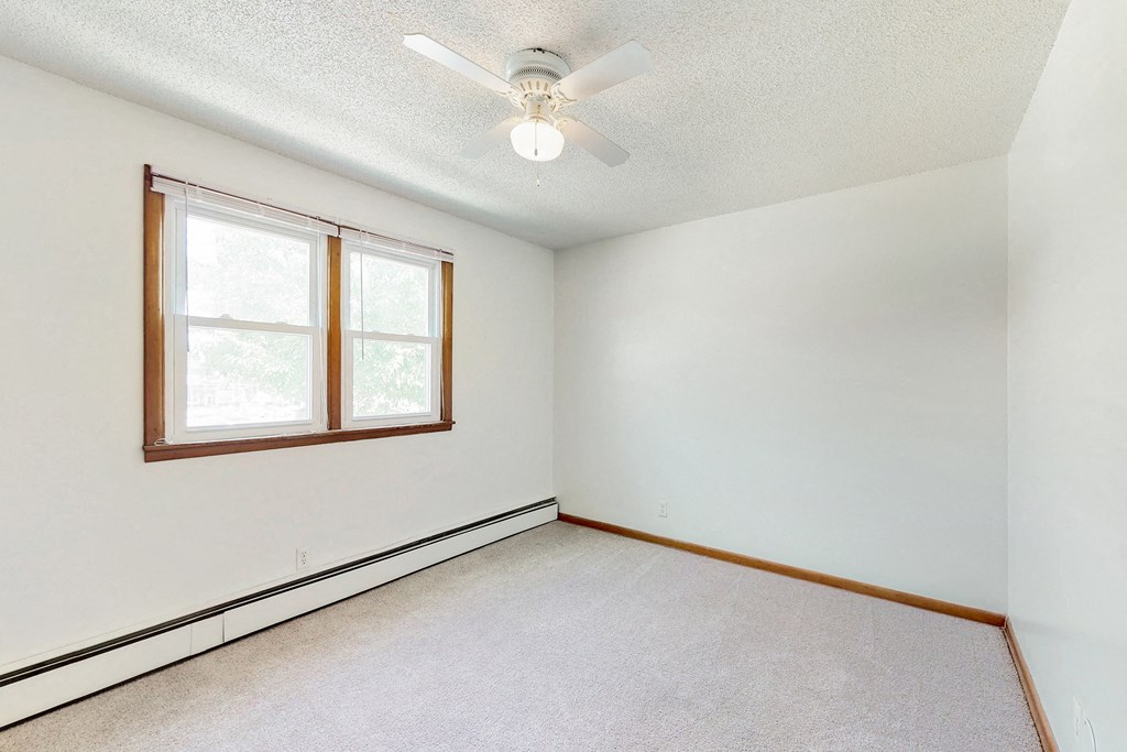 an empty room with a ceiling fan and a window