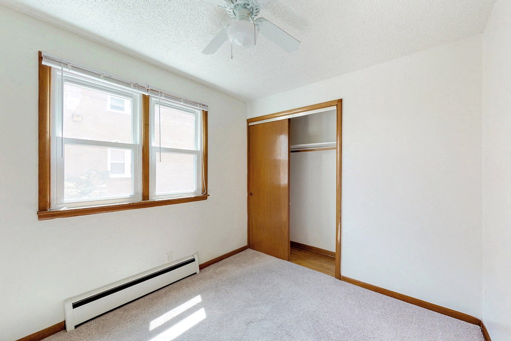 an empty room with a ceiling fan and two windows