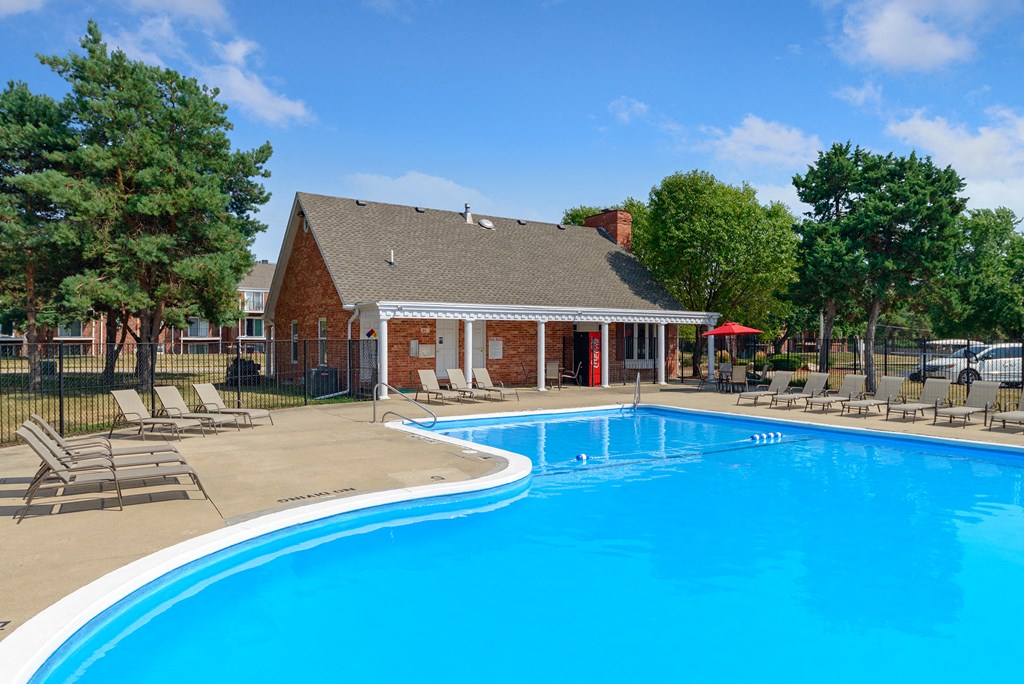 a swimming pool with chairs around it in front of a house