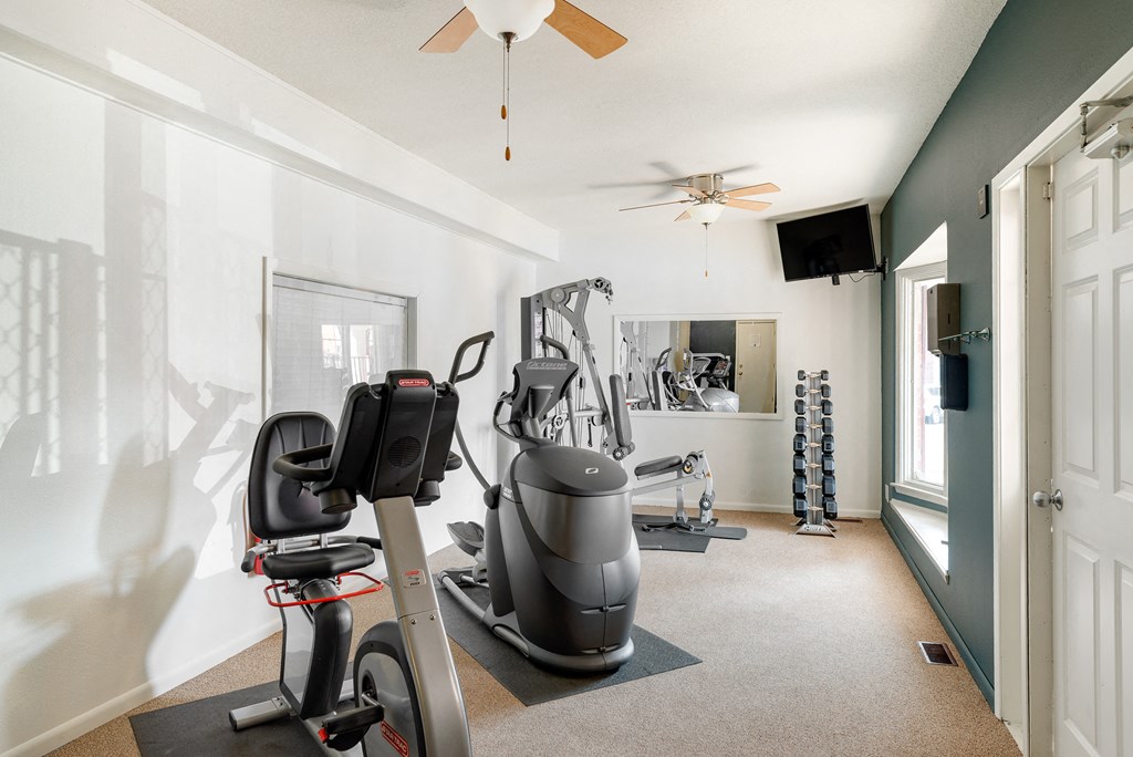 a home gym with exercise equipment and a ceiling fan