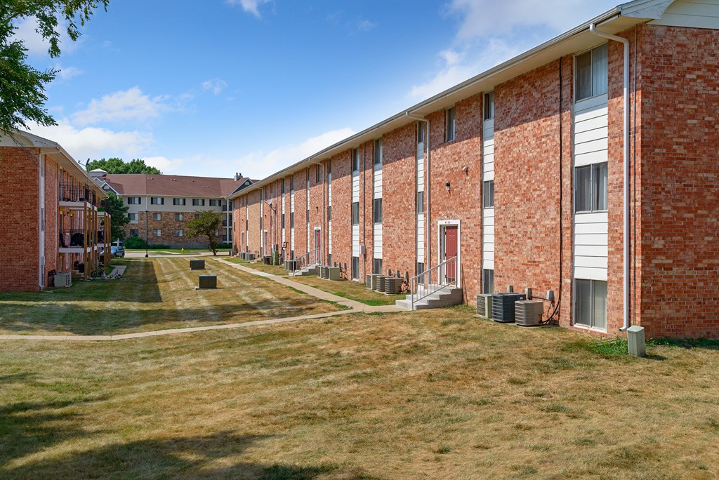 a row of brick apartment buildings on the side of a field