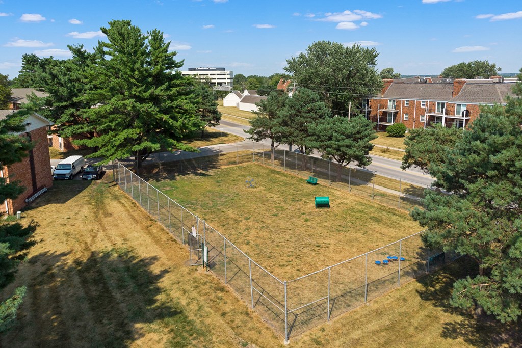 an aerial view of a fenced in area with trees and buildings