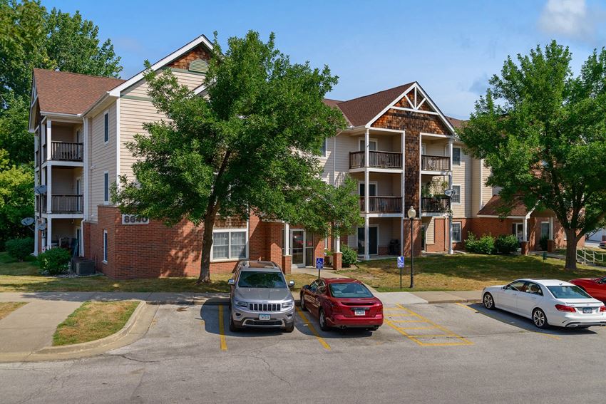 an apartment building with cars parked in a parking lot