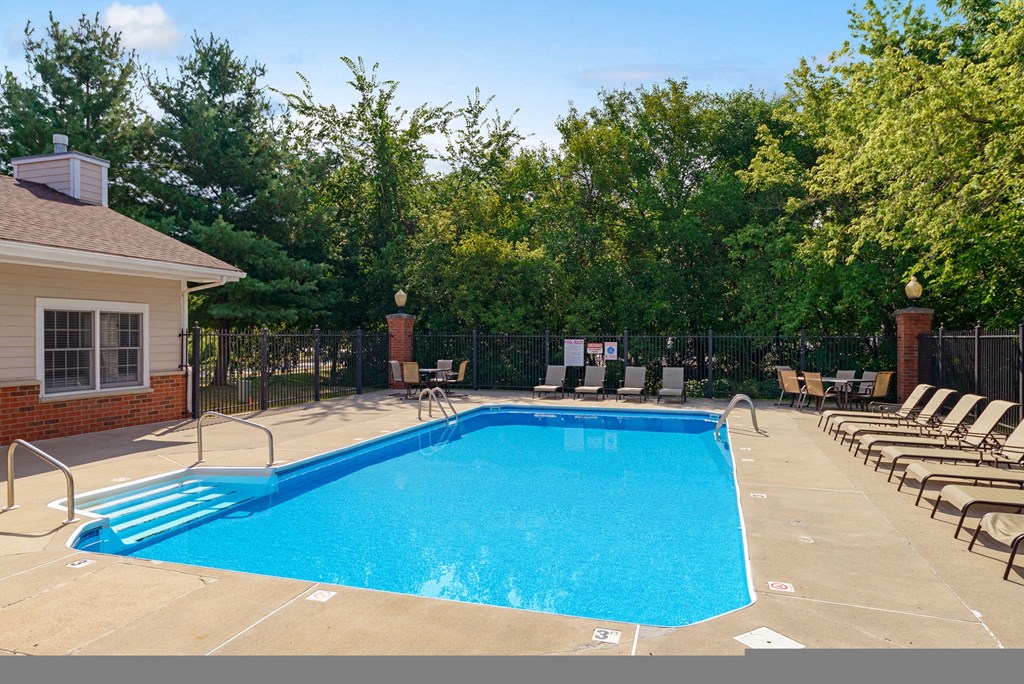 a swimming pool with chairs around it in front of a house