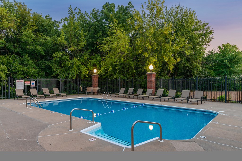 a swimming pool with chairs and trees in the background
