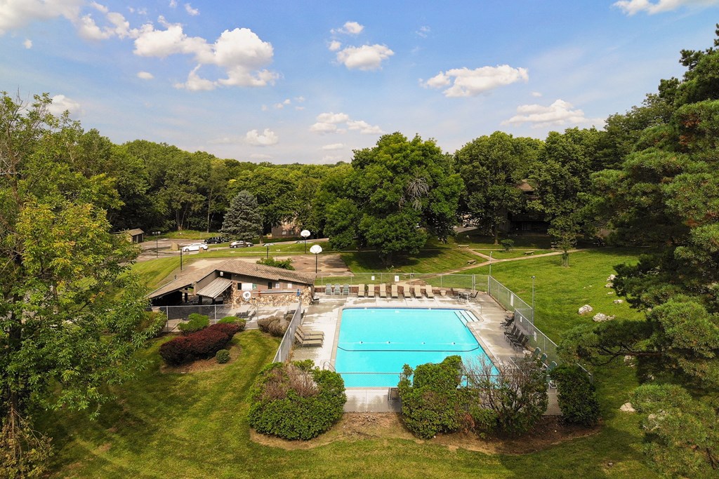 a backyard with a swimming pool and a lawn with trees and a house
