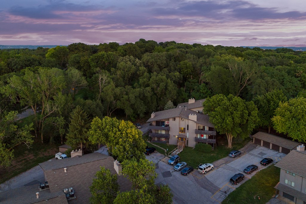 an aerial view of a house surrounded by trees and a parking lot