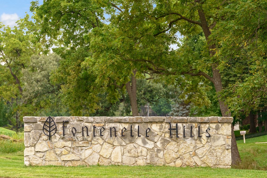 a stone wall with a name on it in front of trees