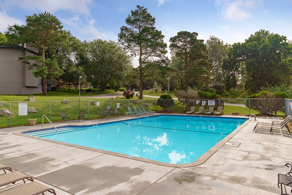 a swimming pool with chairs and a fence around it