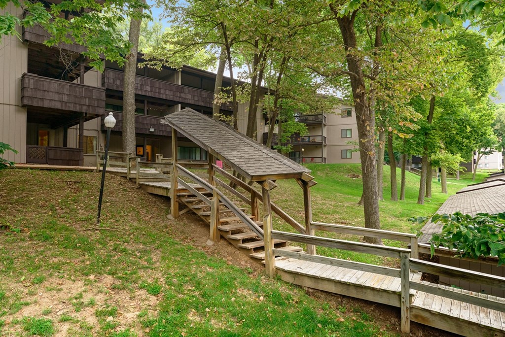 a building with a wooden deck and stairs in the grass