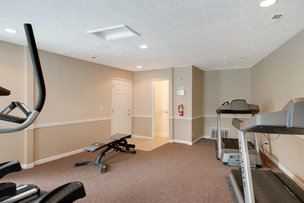 an exercise room with a treadmill and weights