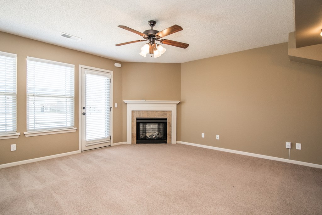 an empty living room with a ceiling fan and a fireplace