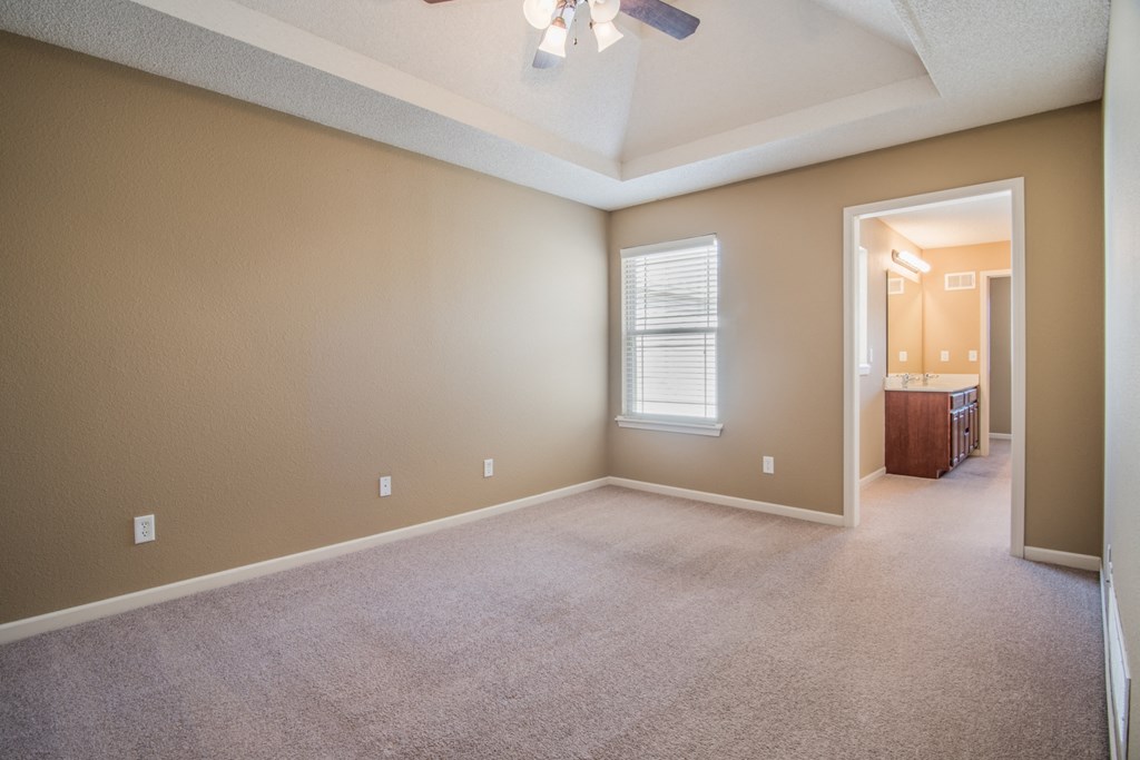 an empty living room with carpet and a ceiling fan