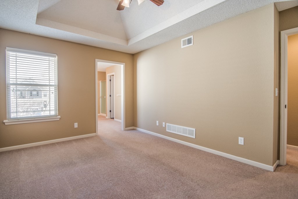 an empty living room with a window and a ceiling fan