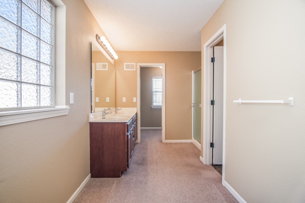 a bathroom with a sink and a mirror and a door to a hallway