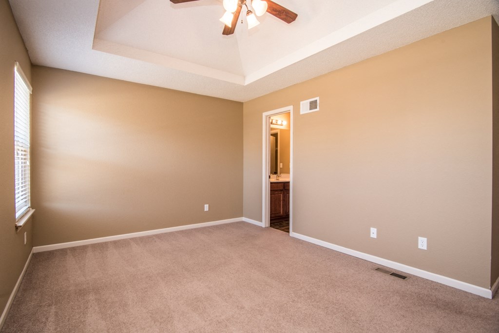an empty living room with a ceiling fan