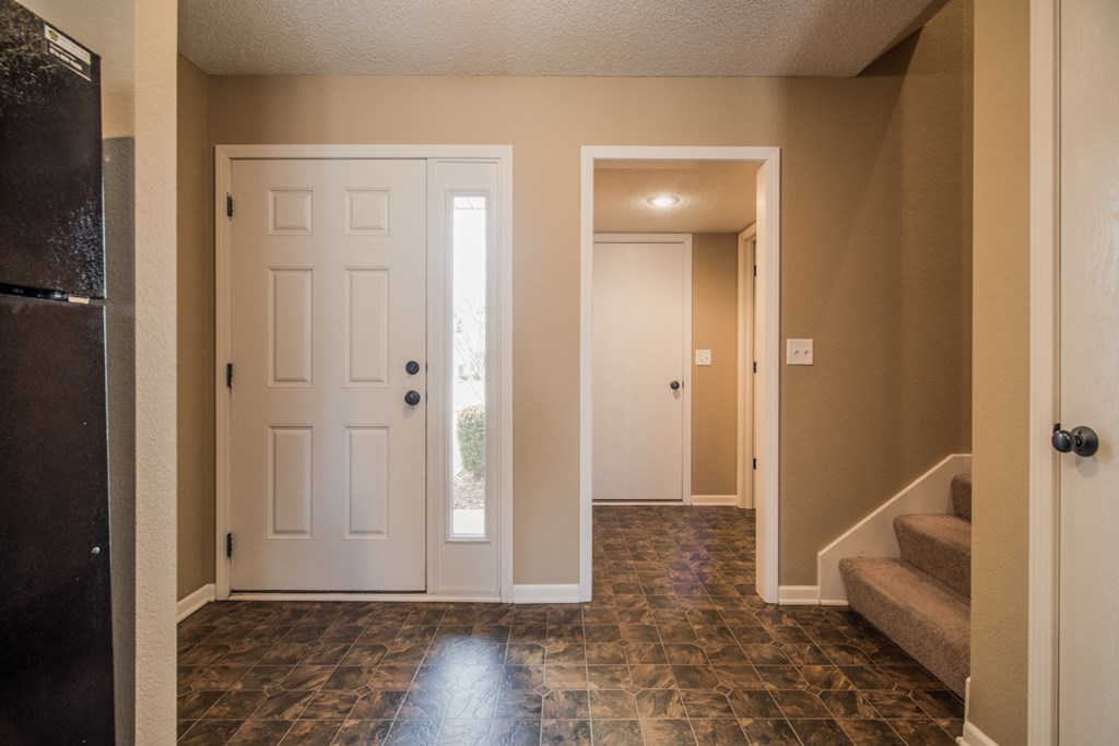 an empty living room with two doors and a staircase