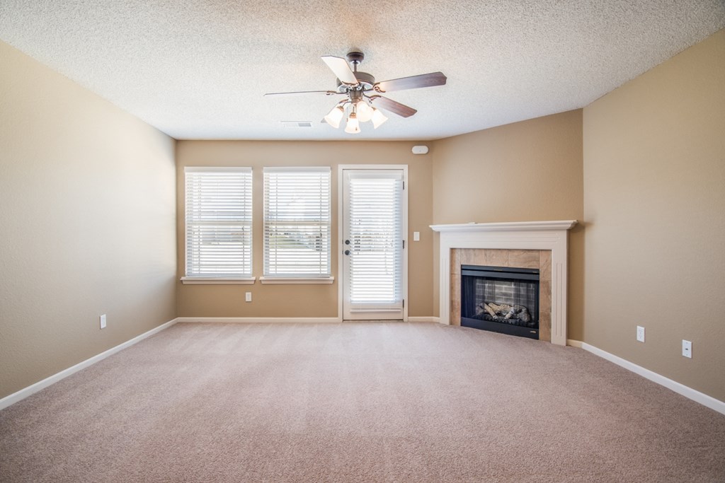 an empty living room with a fireplace and a ceiling fan