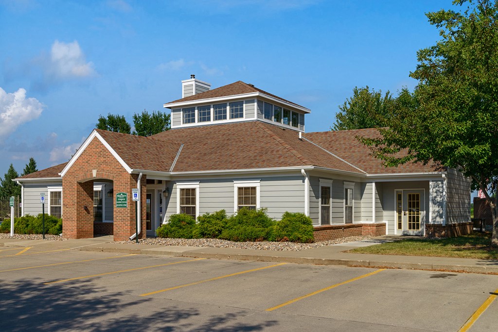 a white building with a brown roof and a parking lot