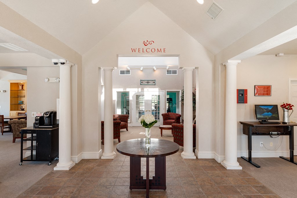 a lobby with a table and chairs and a welcome sign