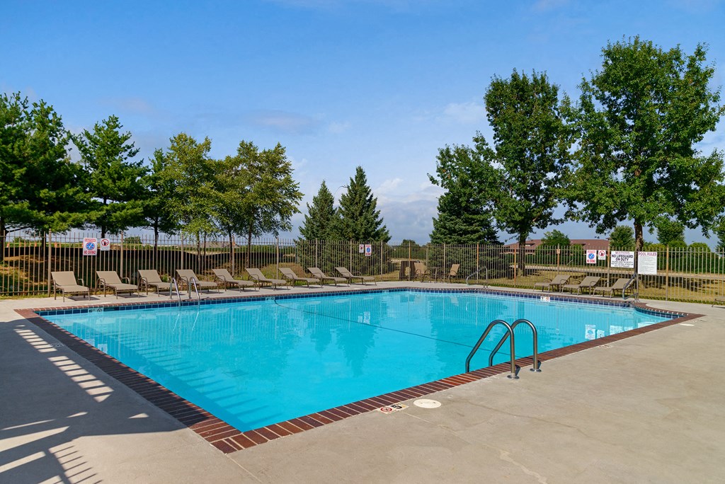a swimming pool with chaise lounge chairs and trees