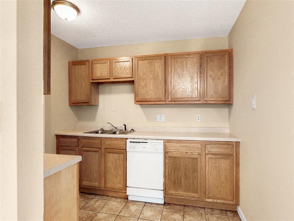 an empty kitchen with wooden cabinets and a white dishwasher