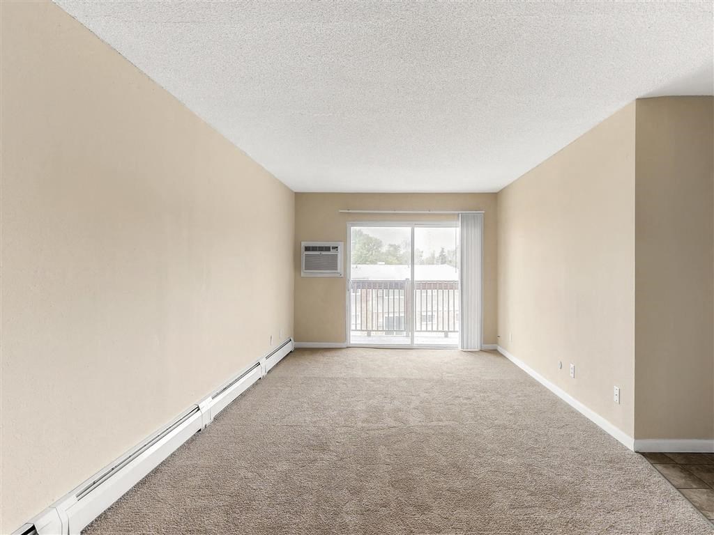 an empty living room with a sliding glass door to a balcony