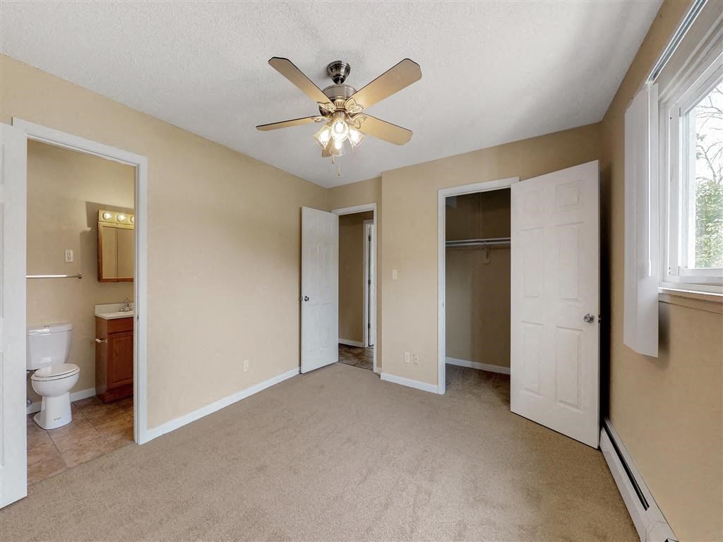 an empty living room with a ceiling fan and a bathroom