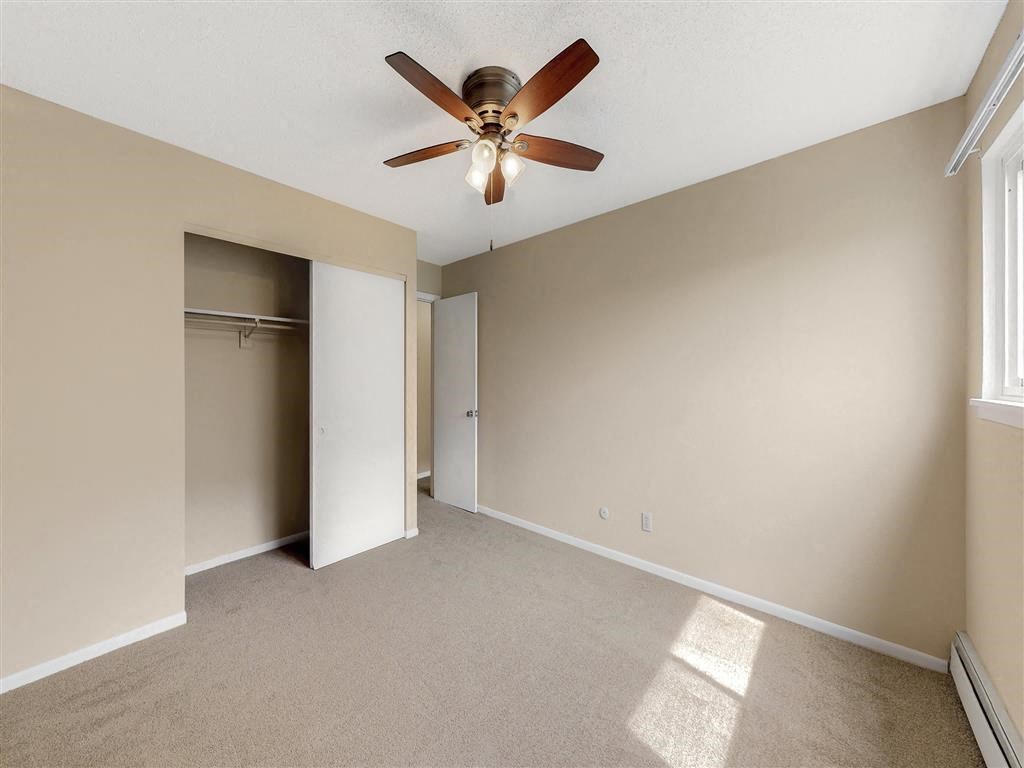 an empty living room with a ceiling fan and a closet