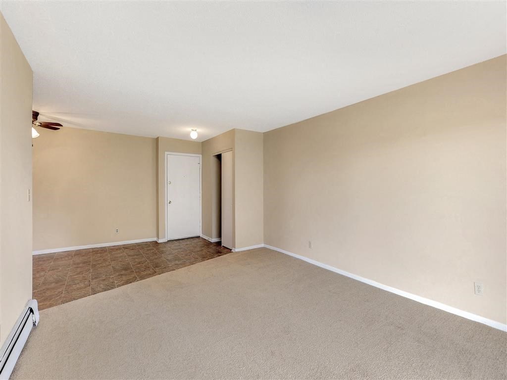 an empty living room with carpet and a door to a closet