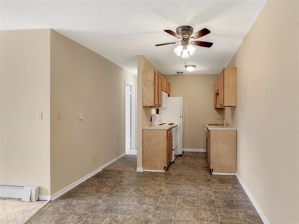 an empty kitchen with a ceiling fan and cabinets