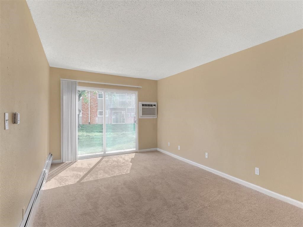 an empty living room with a sliding glass door to a yard