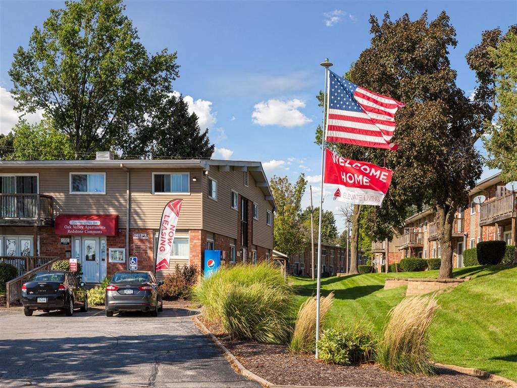 an apartment building flags and cars parked