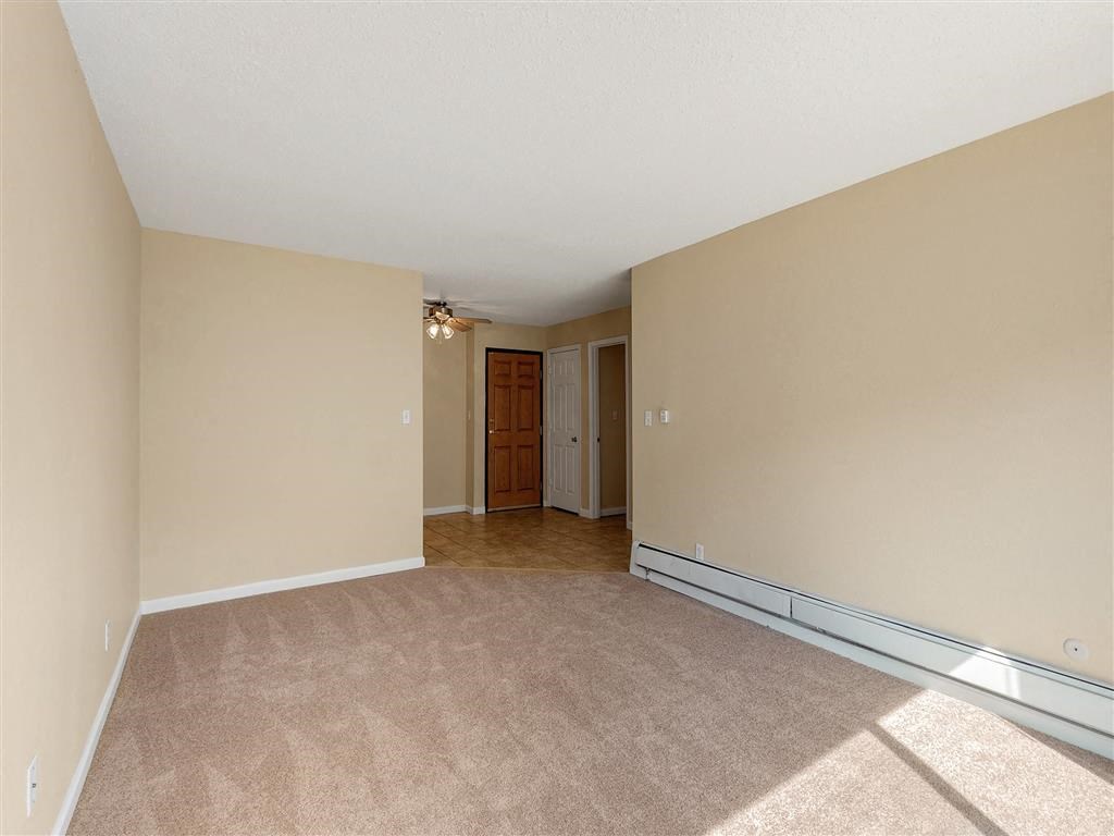 an empty living room with carpet and a door to a hallway