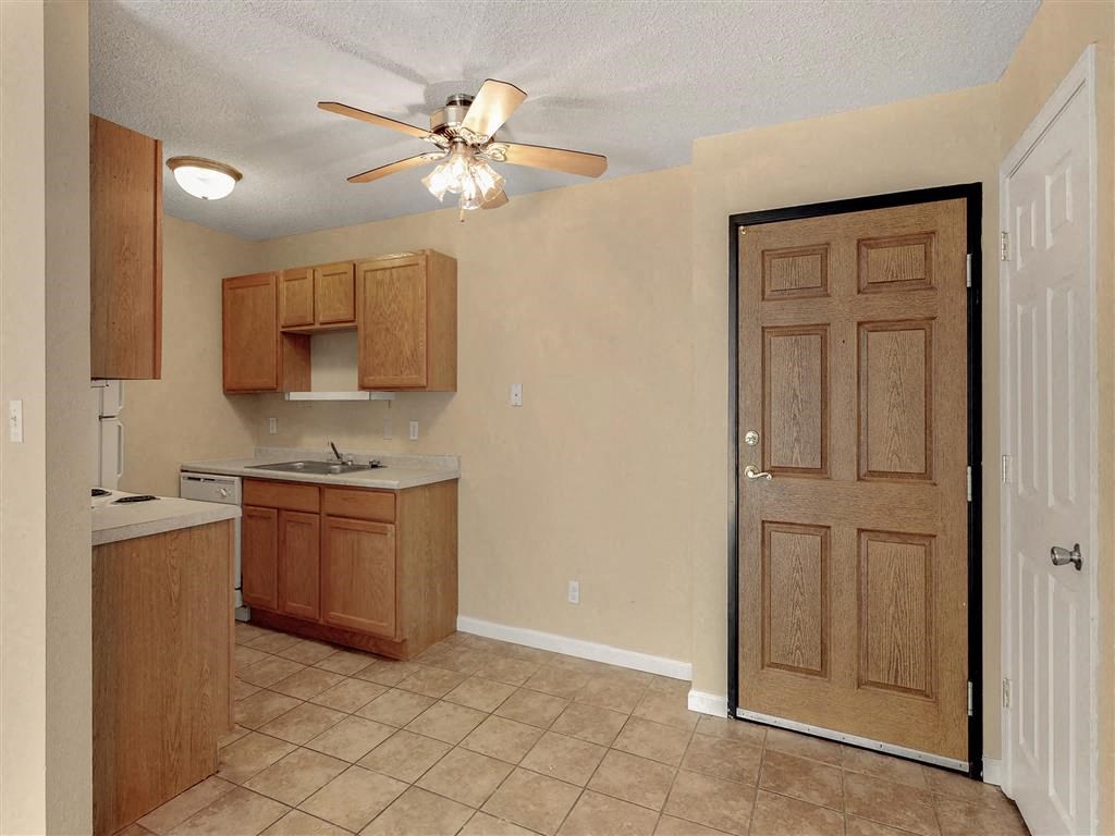 an empty kitchen with a ceiling fan and a door