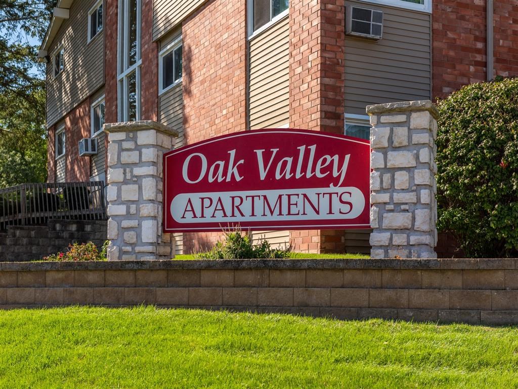 a sign for oak valley apartments in front of a brick building