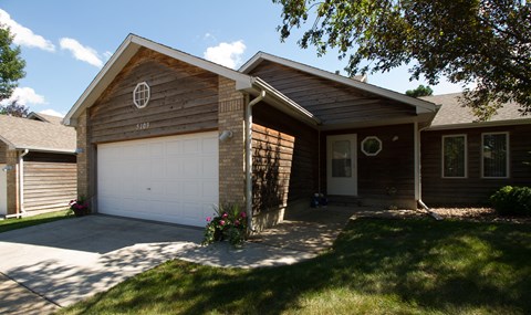 A house with a brown wooden exterior and a white garage door.
