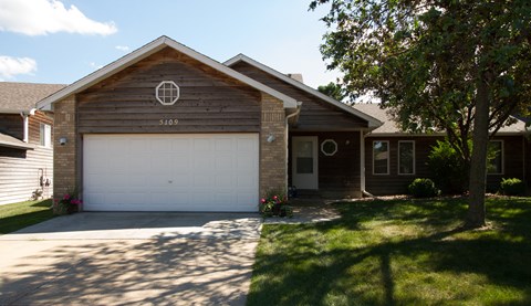 A house with a garage door and a tree in front.