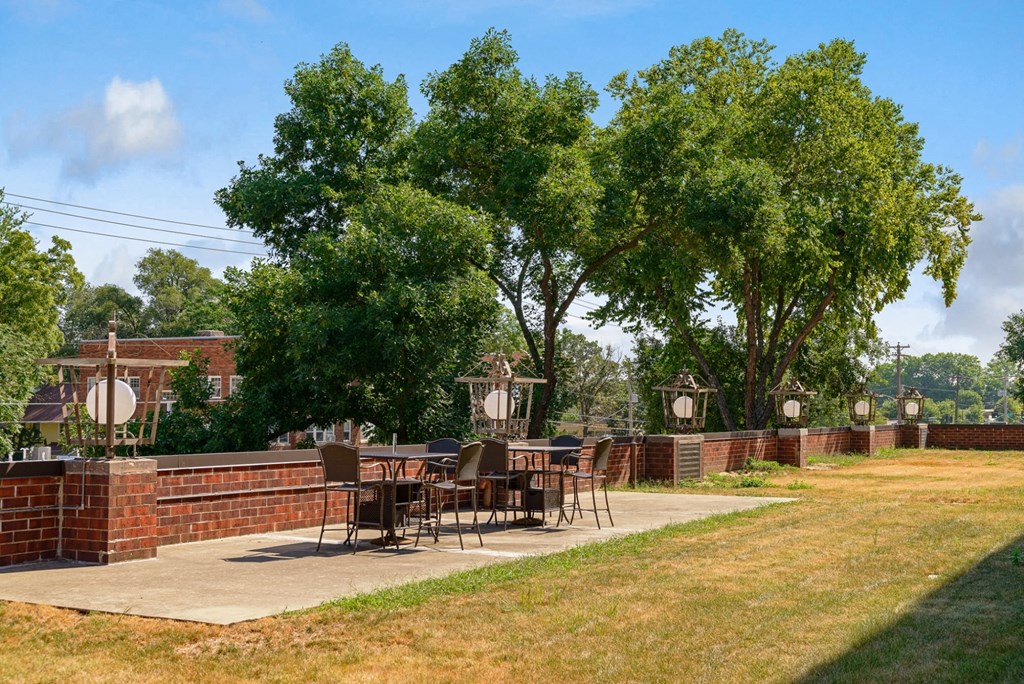 a patio with tables and chairs in a backyard with trees