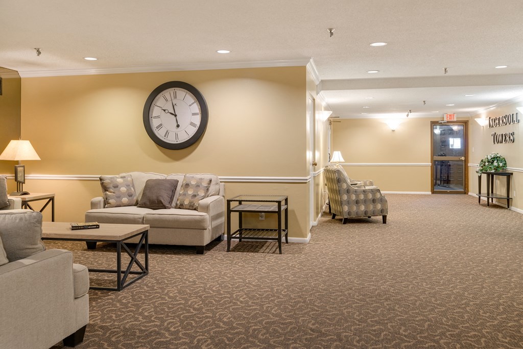 a lobby with couches and chairs and a clock on the wall